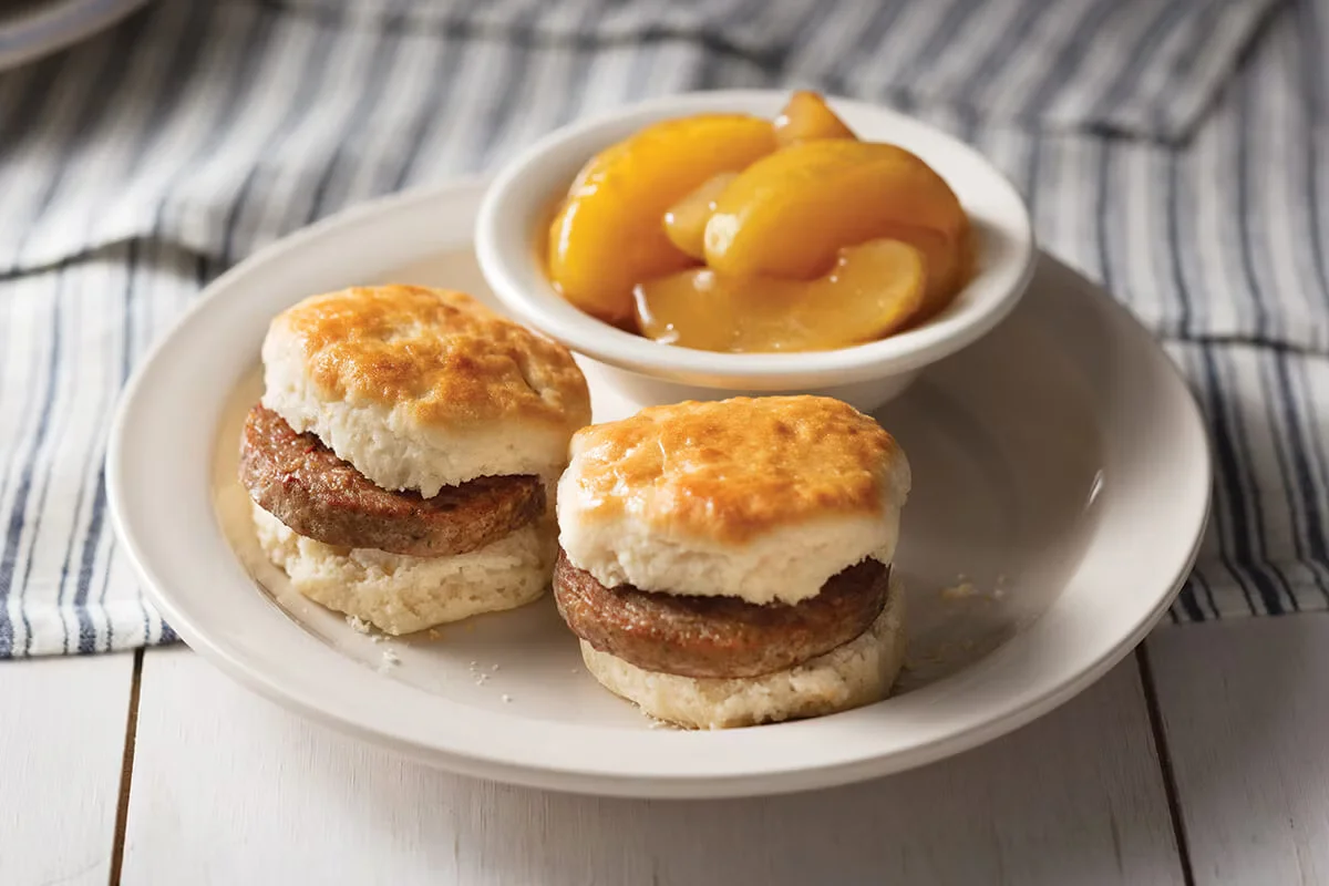 Cracker Barrel's Biscuit Breakfast with fluffy buttermilk biscuits, eggs, sausage or bacon, and a side of hashbrowns or fried apples.