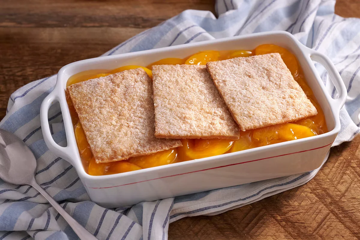 Cracker Barrel's Peach Cobbler with sweet peach filling and a golden, flaky crust, served with vanilla ice cream.