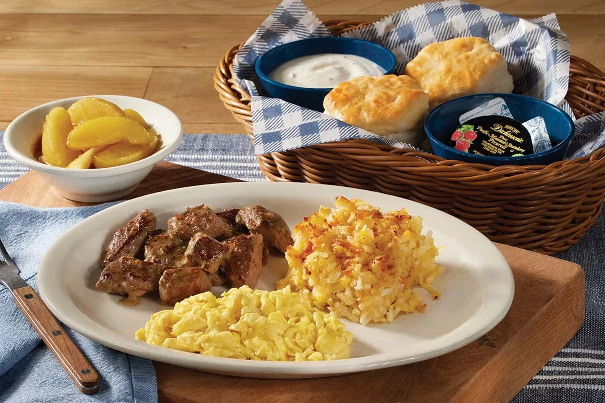 Cracker Barrel's Country Boy Breakfast with eggs, ham, hashbrowns, and biscuits served with grits and sides.